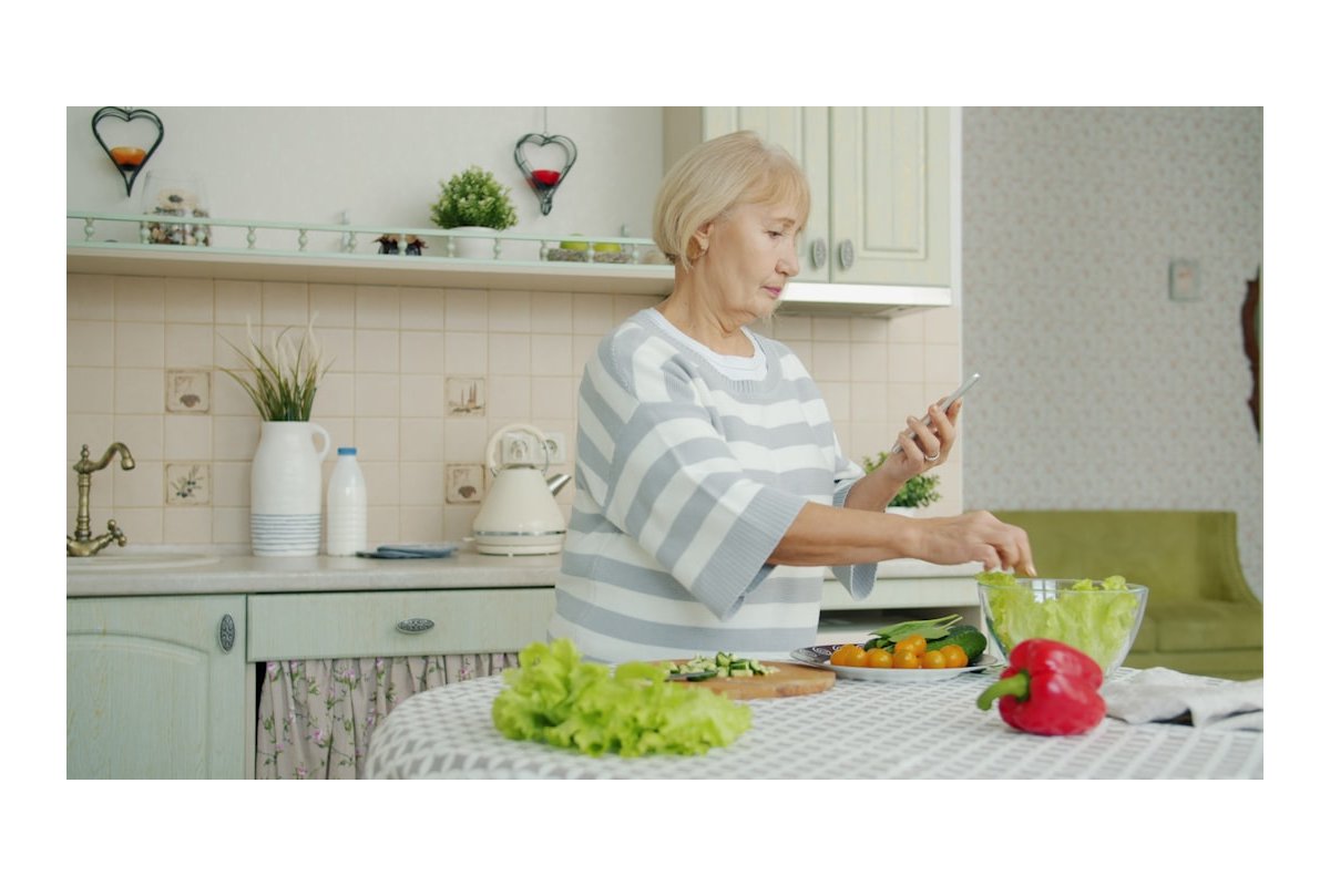 Elderly woman preparing salad in a kitchen
