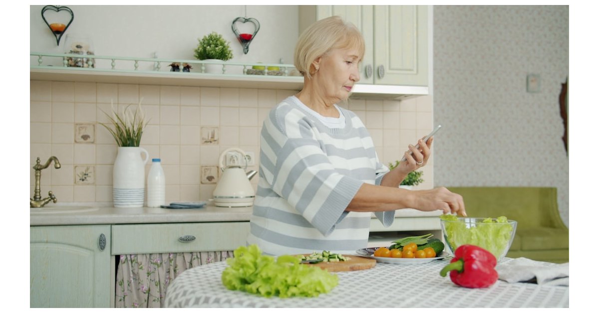 Elderly woman preparing salad in a kitchen
