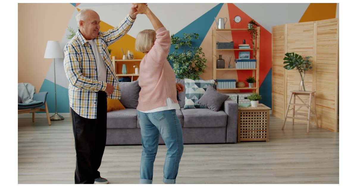 Elderly couple dancing joyfully in a living room.